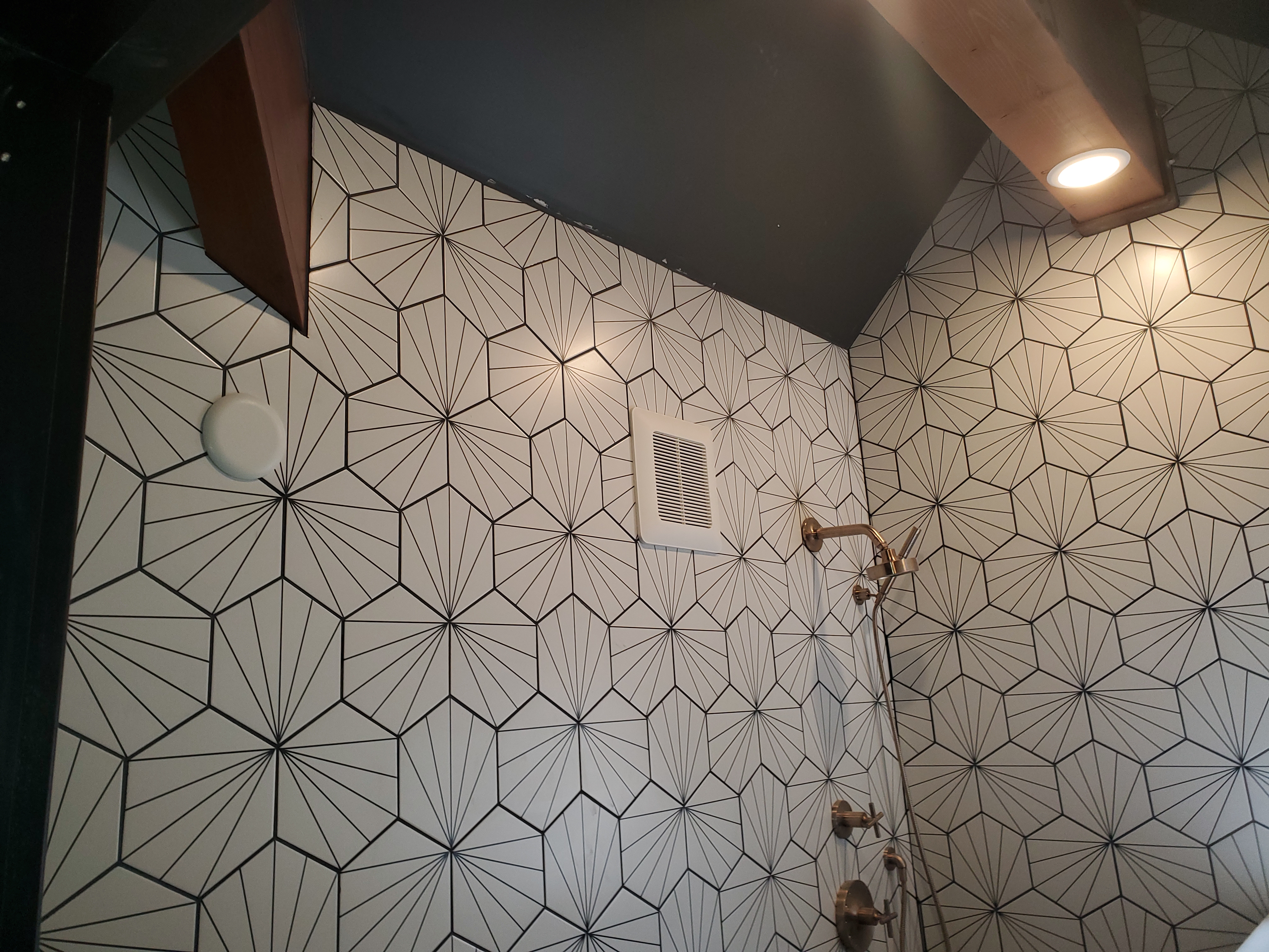 Geometric starburst tile pattern covering shower walls and ceiling