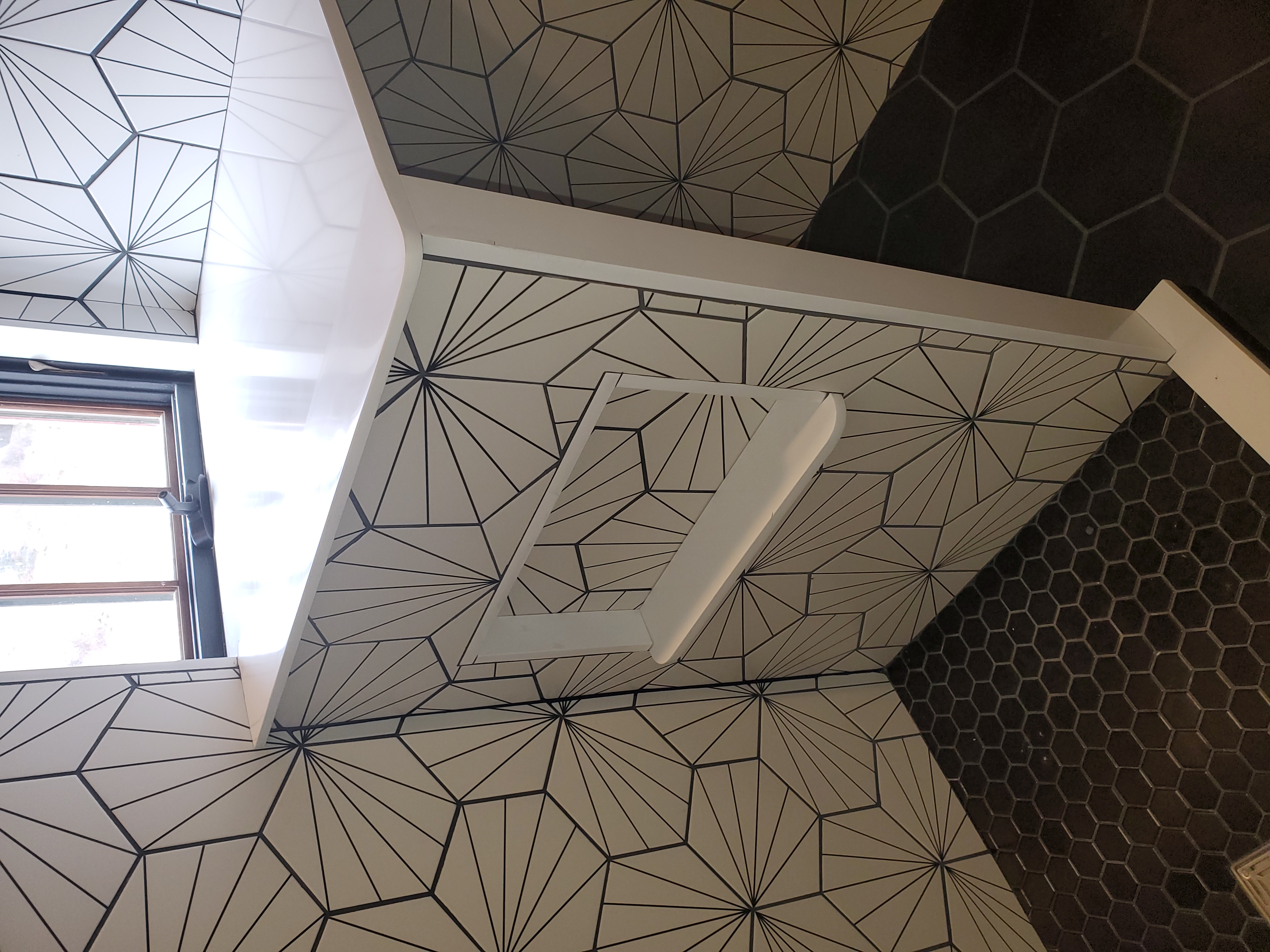 Geometric tile wrapping corner with dark hexagon ceiling tile accent